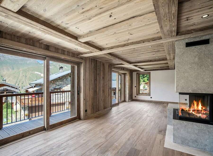 Experience luxurious alpine living in this stunning mountain retreat, featuring a modern fireplace and expansive glass doors that open to breathtaking panoramic views.