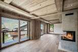 Experience luxurious alpine living in this stunning mountain retreat, featuring a modern fireplace and expansive glass doors that open to breathtaking panoramic views.