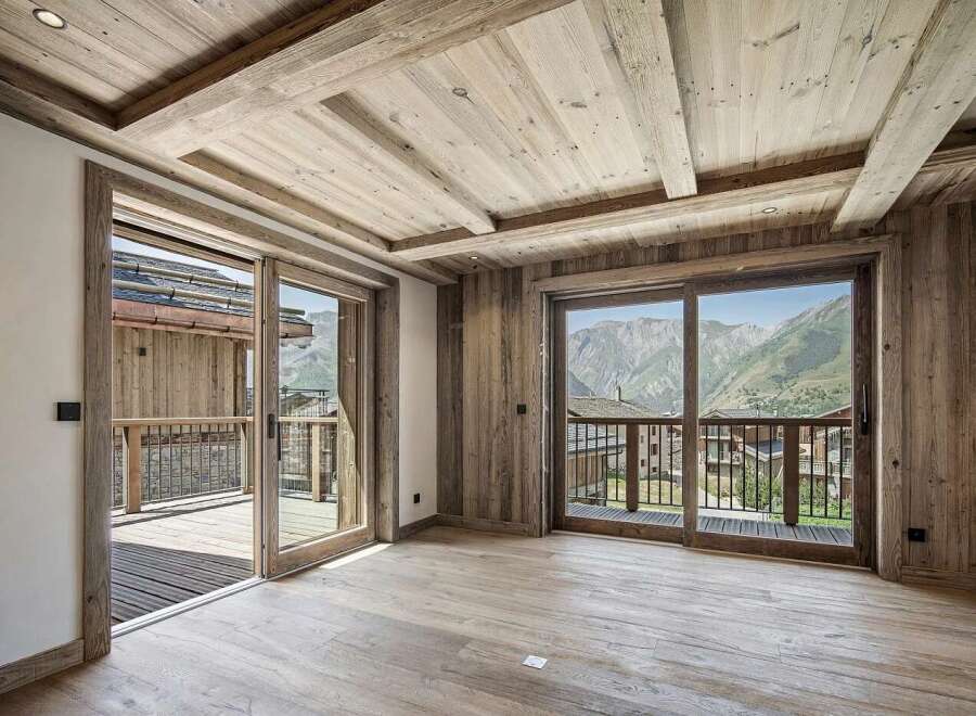 Experience luxury mountain living in this stunning property featuring a rustic yet modern interior with exposed wooden beams and paneling.