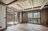 Experience luxury mountain living in this stunning property featuring a rustic yet modern interior with exposed wooden beams and paneling.