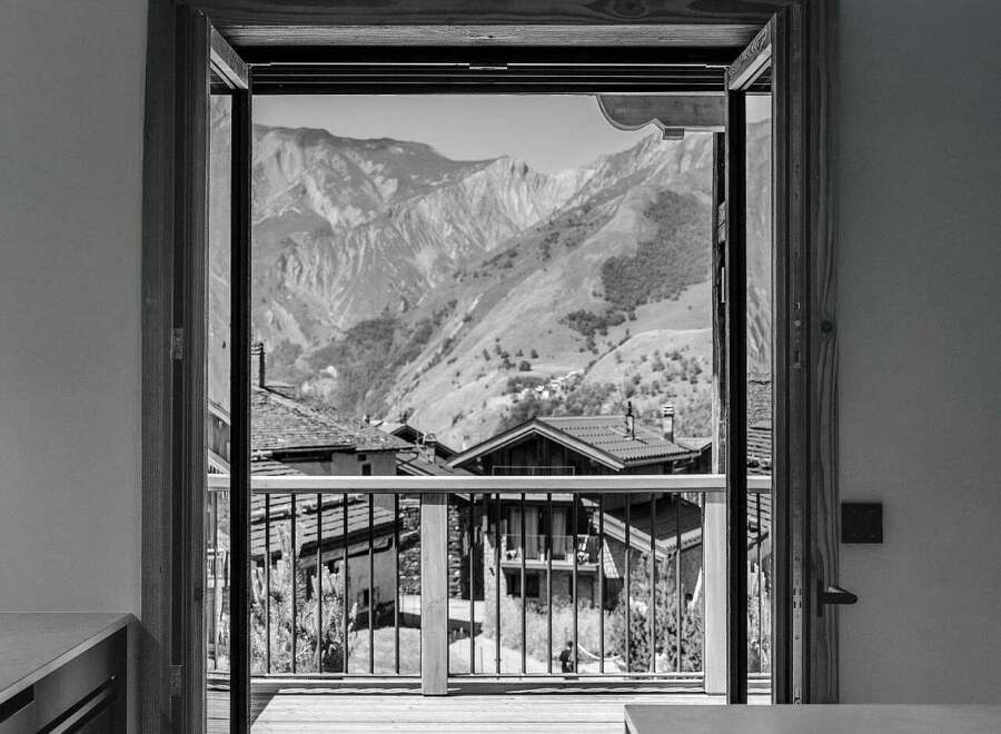 Experience breathtaking mountain views from this stunning property, framed by an open doorway leading to a spacious wooden deck.