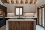 Experience rustic charm and modern convenience in this stunning kitchen, featuring a warm wooden island and exposed beam ceiling.
