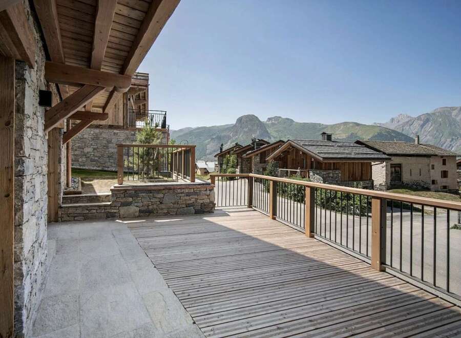 Experience breathtaking mountain views from this stunning property featuring a spacious wooden deck and a charming stone exterior.