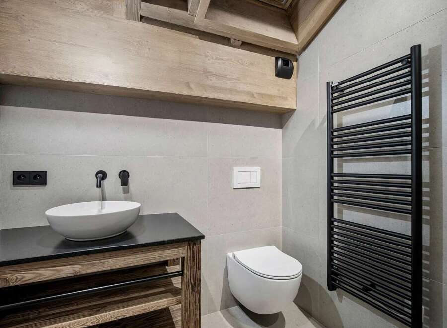 Experience modern luxury in this stunning bathroom, featuring a sleek vessel sink atop a rustic wooden vanity.