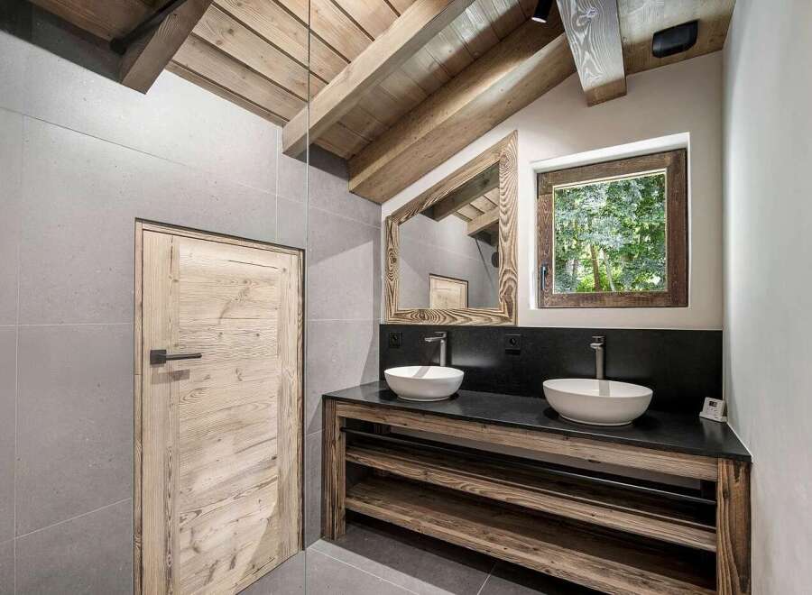 Experience rustic charm in this mountain-inspired bathroom, featuring a double vanity with vessel sinks set against a dark stone countertop.