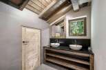 Experience rustic charm in this mountain-inspired bathroom, featuring a double vanity with vessel sinks set against a dark stone countertop.