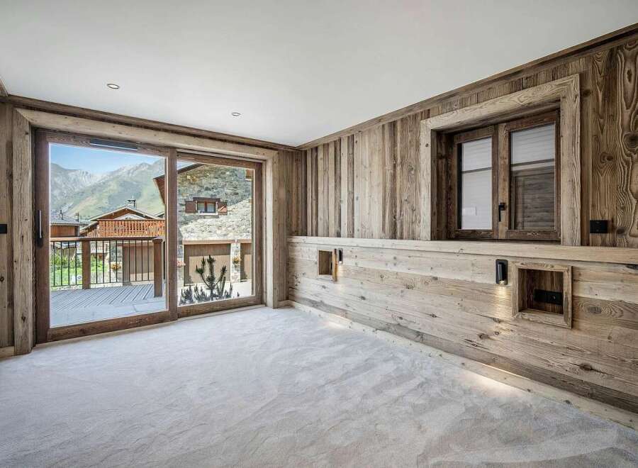 Experience luxurious mountain living in this beautifully appointed bedroom, featuring rustic wood paneling and a plush carpeted floor.