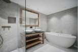 Experience modern luxury in this stunning bathroom, featuring a freestanding soaking tub and a spacious walk-in shower with sleek grey tiling.