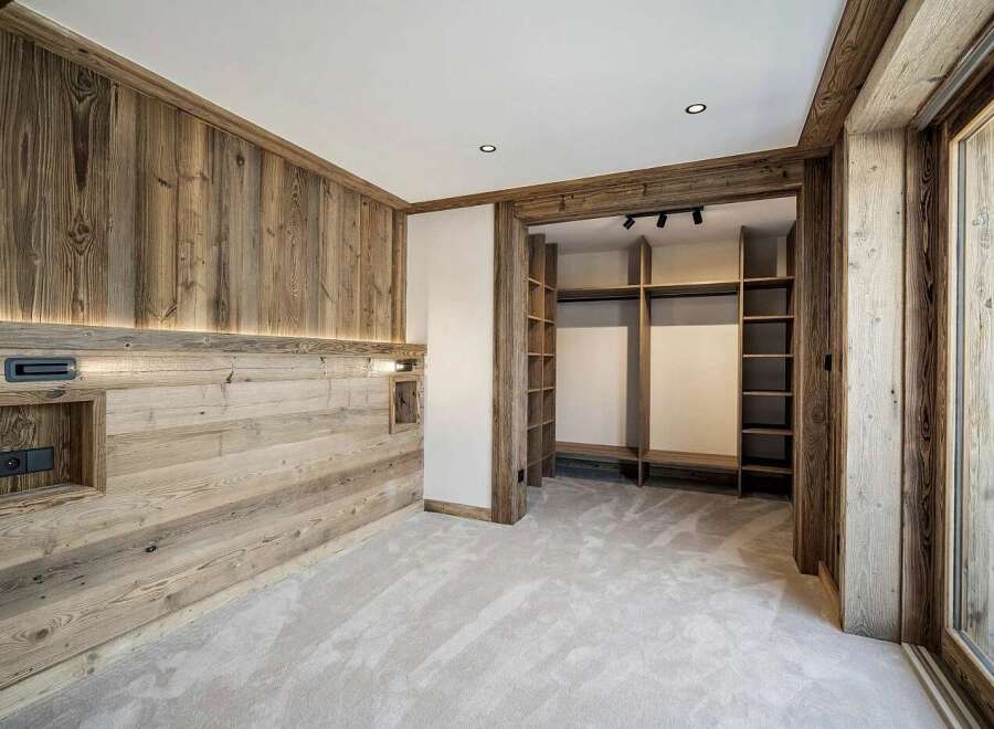 Experience rustic luxury in this bedroom featuring warm, natural wood paneling and integrated lighting.