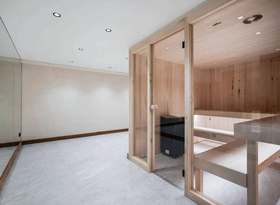 Experience ultimate relaxation in this modern home spa featuring a beautifully crafted wooden sauna with glass doors.