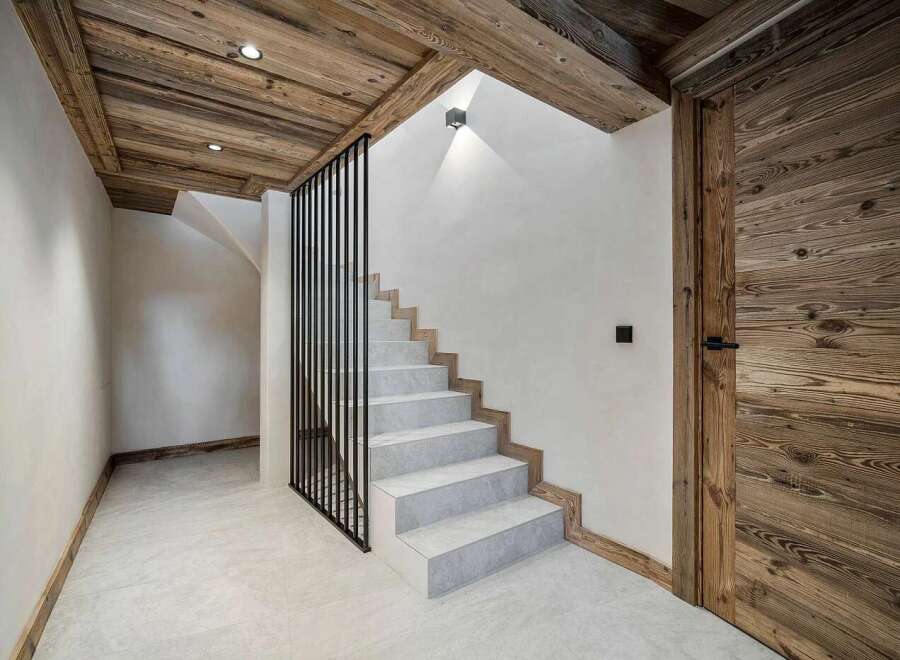 Experience rustic charm and modern elegance in this stunning entryway, featuring a beautiful wooden ceiling and a sleek staircase with a black metal railing.