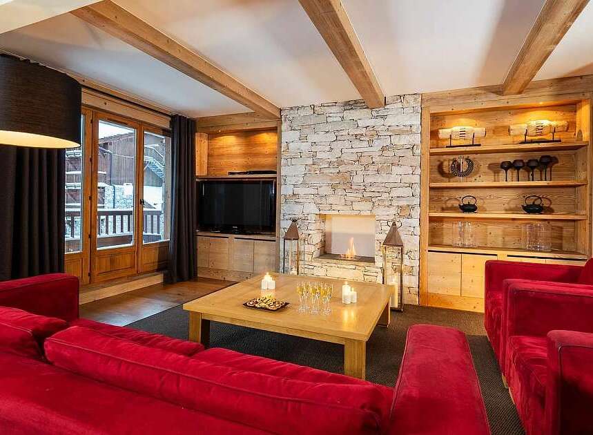 Experience luxurious mountain living in this stunning living room, featuring a cozy stone fireplace and elegant wooden beams.