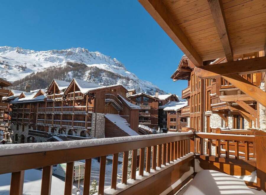Experience the charm of a winter wonderland from this stunning balcony, offering breathtaking views of snow-capped mountains and traditional wooden chalets.