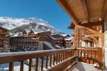 Experience the charm of a winter wonderland from this stunning balcony, offering breathtaking views of snow-capped mountains and traditional wooden chalets.