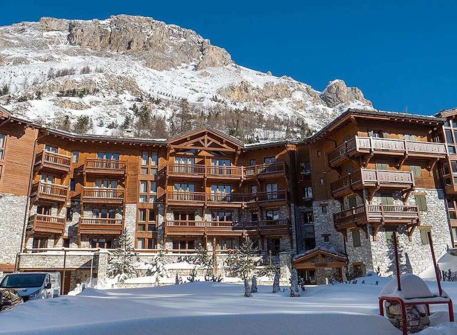 Experience luxury mountain living in this stunning ski resort property, featuring a grand wooden and stone facade that blends seamlessly with the snow-capped peaks.