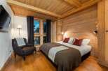 Experience cozy mountain living in this charming bedroom featuring warm wood paneling and exposed beams.