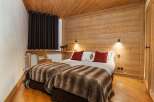 Experience cozy mountain living in this charming bedroom featuring two comfortable beds adorned with plush, striped throws and vibrant red accent pillows.