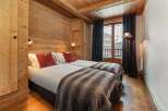 Experience cozy mountain living in this charming bedroom featuring two comfortable twin beds adorned with plush red pillows and soft, faux fur throws.