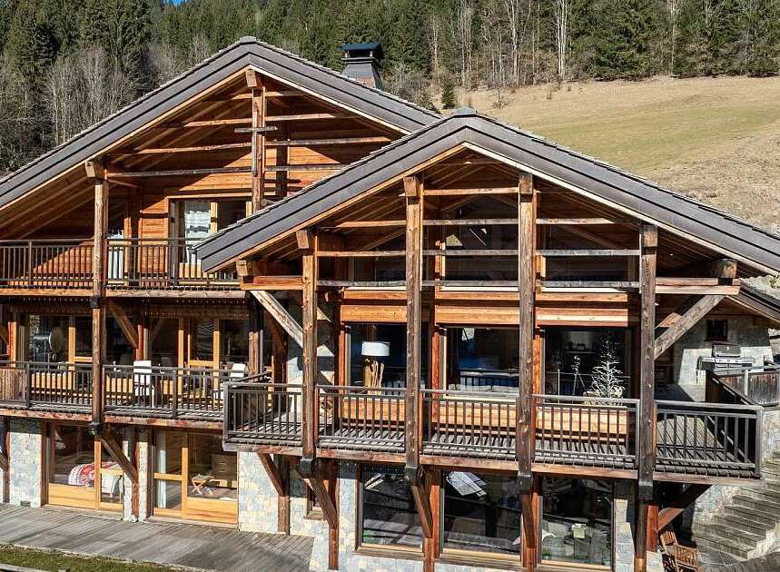 Experience luxury mountain living in this stunning chalet, featuring a multi-level wooden structure with expansive balconies offering breathtaking views.