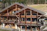 Experience luxury mountain living in this stunning chalet, featuring a multi-level wooden structure with expansive balconies offering breathtaking views.