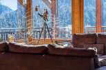 Experience breathtaking mountain views from this cozy living room, featuring a large telescope perfect for stargazing or wildlife observation.