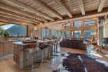 Experience luxury mountain living in this stunning chalet, featuring a spacious open-plan living area with a modern kitchen island and comfortable seating.