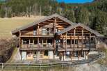 Experience luxury mountain living in this stunning chalet, featuring expansive wooden balconies and large windows that offer breathtaking forest views.