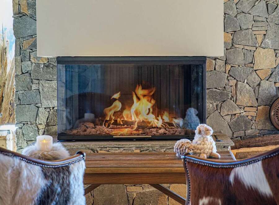 Experience cozy evenings by this stunning stone fireplace, featuring a modern glass enclosure and a warm, inviting flame.