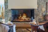 Experience cozy evenings by this stunning stone fireplace, featuring a modern glass enclosure and a warm, inviting flame.