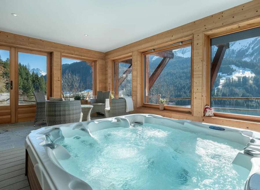 Indulge in ultimate relaxation in this luxurious indoor hot tub, boasting stunning panoramic views of snow-capped mountains and lush forests.