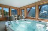 Indulge in ultimate relaxation in this luxurious indoor hot tub, boasting stunning panoramic views of snow-capped mountains and lush forests.
