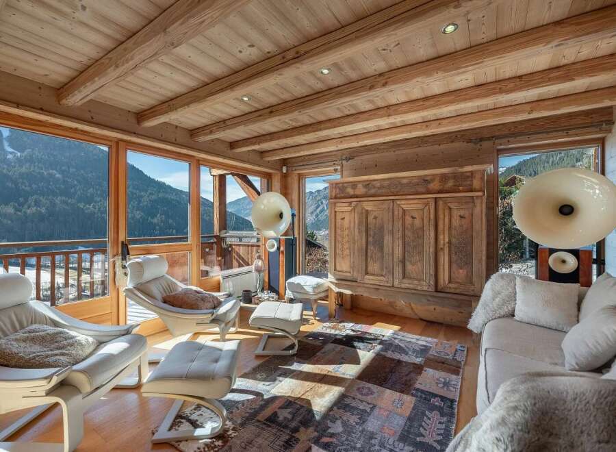 Experience breathtaking mountain views from this stunning living room, featuring a cozy fireplace and expansive windows.