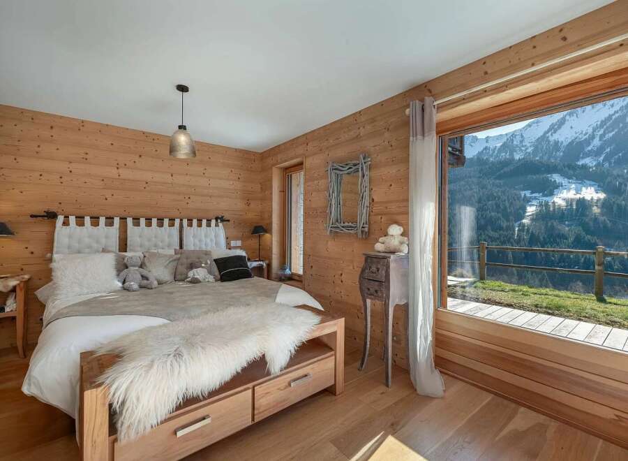 Experience luxury mountain living in this stunning bedroom, featuring warm wood paneling and a plush king-sized bed.