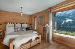 Experience luxury mountain living in this stunning bedroom, featuring warm wood paneling and a plush king-sized bed.
