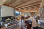 Experience rustic luxury in this stunning mountain chalet, featuring a grand stone fireplace and exposed wooden beams that create a warm and inviting atmosphere.