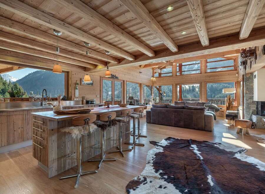 Experience luxury mountain living in this stunning chalet, featuring a spacious open-plan living area with a modern kitchen island and comfortable seating.