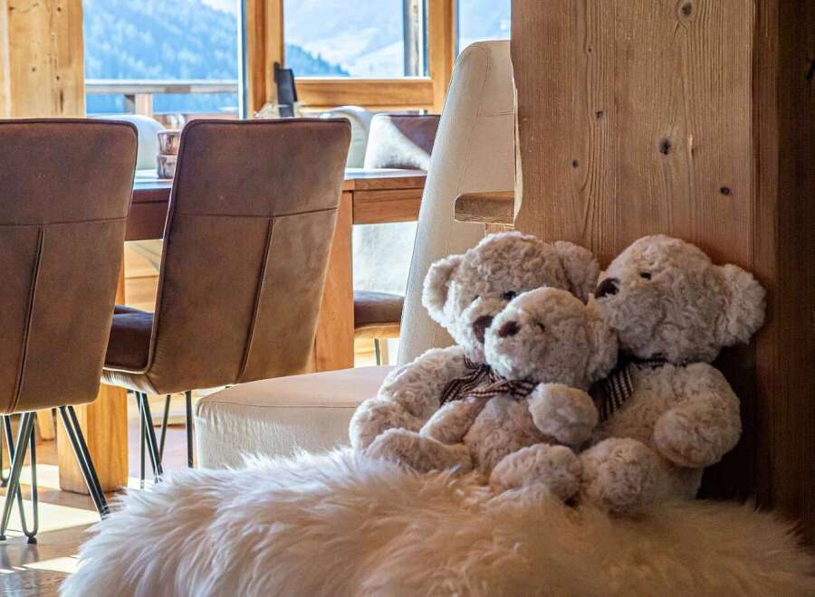 Experience cozy mountain living in this charming property, featuring a warm and inviting dining area with plush seating and large windows offering breathtaking views of the snowy landscape.