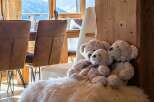 Experience cozy mountain living in this charming property, featuring a warm and inviting dining area with plush seating and large windows offering breathtaking views of the snowy landscape.