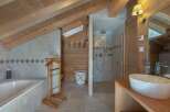 Experience rustic charm in this mountain-view bathroom featuring a luxurious soaking tub and a separate glass-enclosed shower.