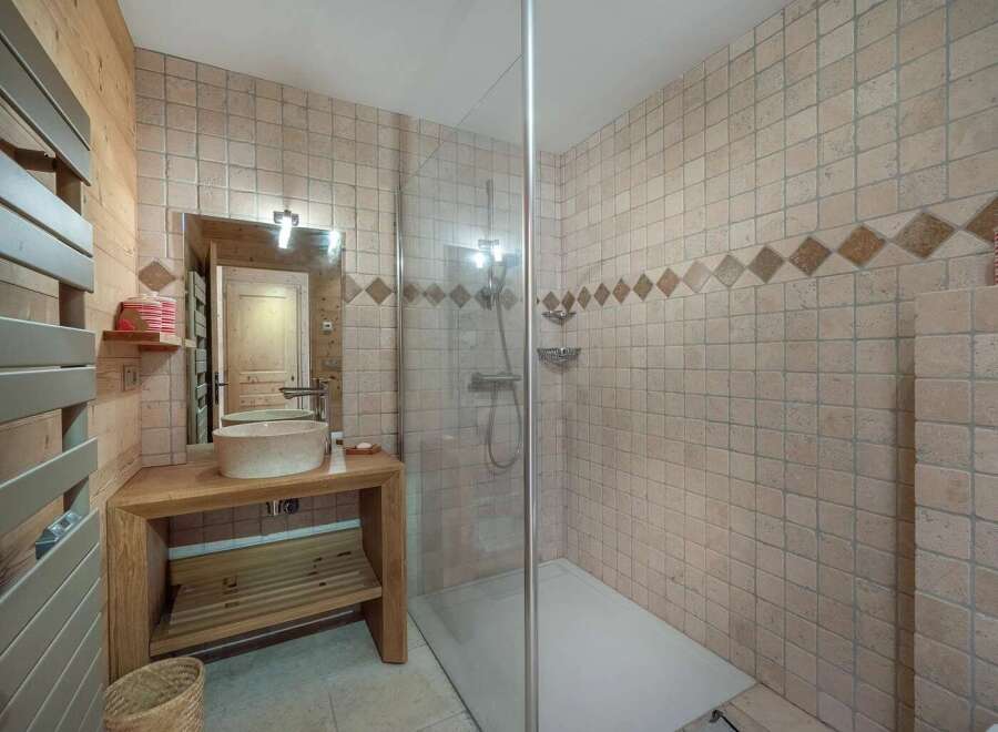 Experience rustic charm in this bathroom featuring a stone vessel sink atop a wooden vanity.