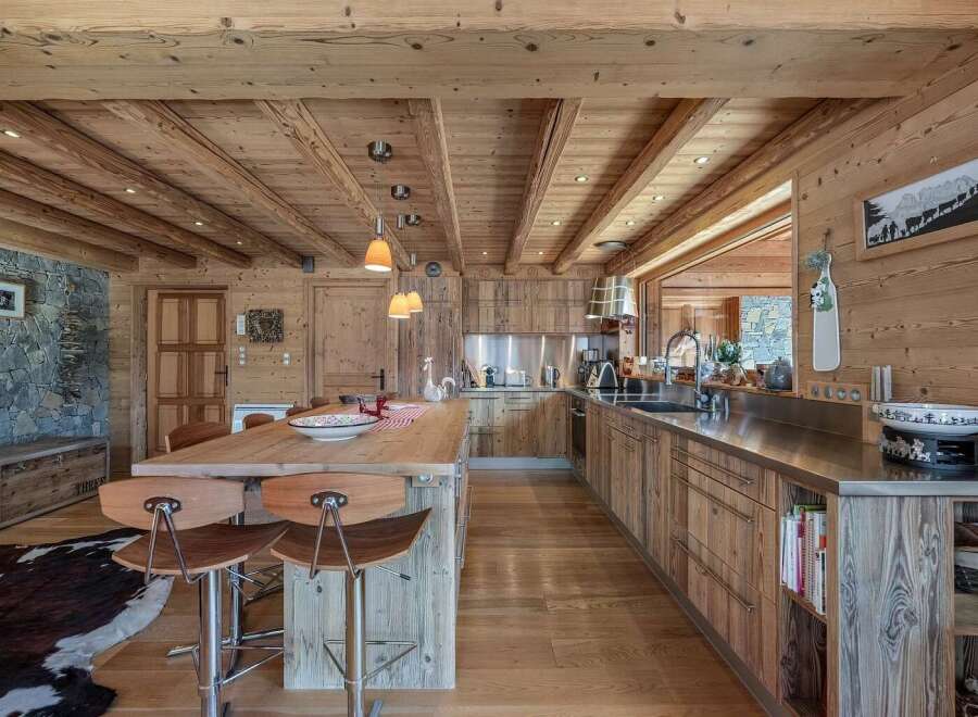Experience rustic luxury in this stunning mountain chalet kitchen, featuring warm wooden cabinetry and exposed beams that create a cozy, inviting atmosphere.