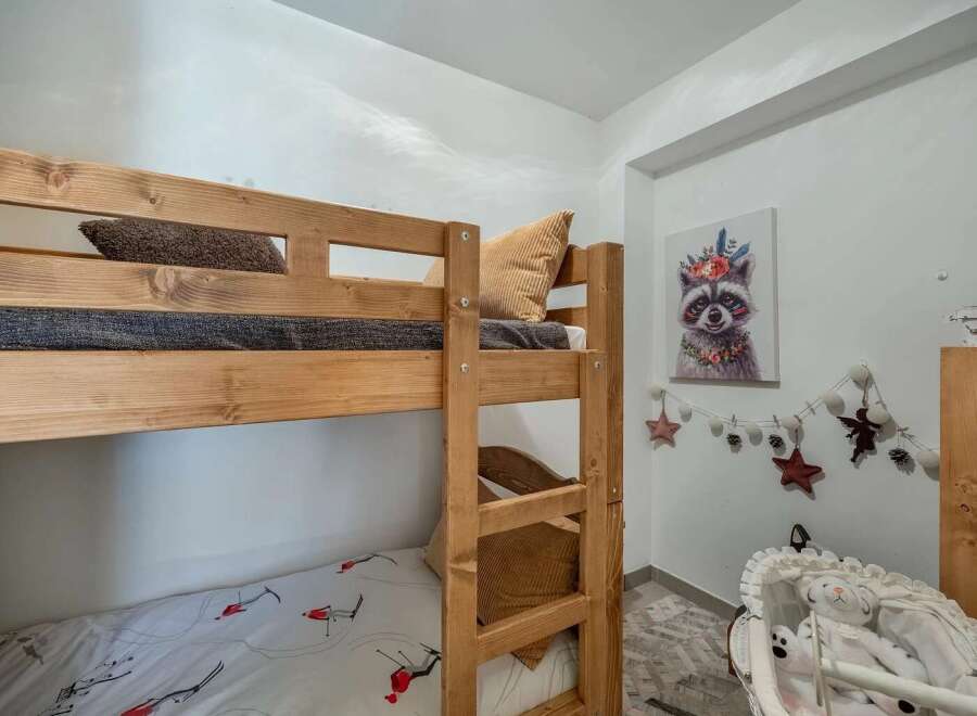 This charming children's room features a sturdy wooden bunk bed, perfect for siblings or sleepovers.