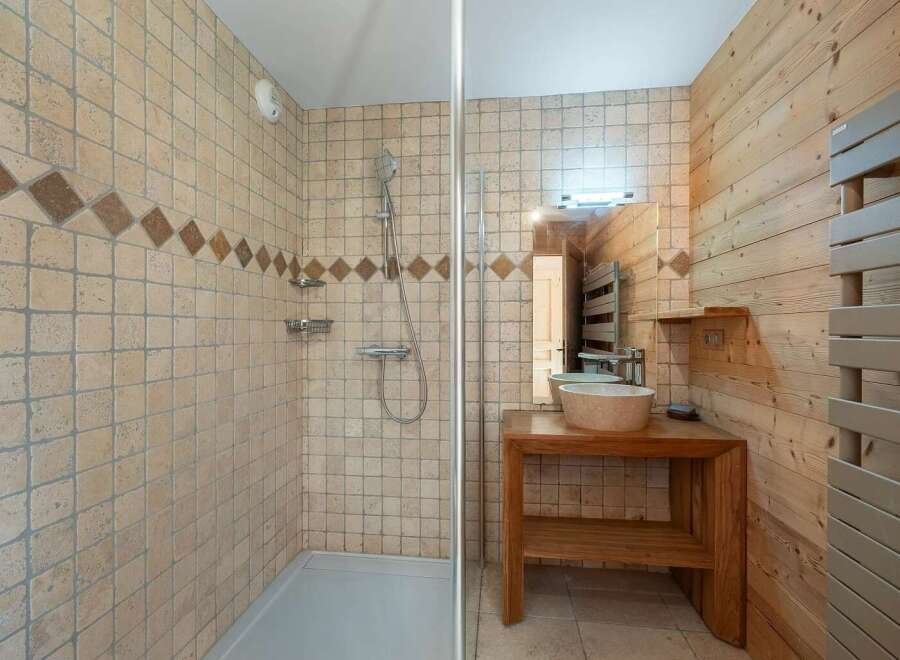 This charming bathroom features a spacious walk-in shower with elegant tiled walls and a decorative diamond accent band.