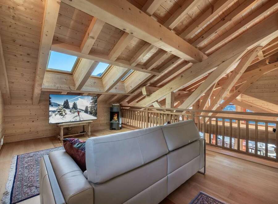 Experience the ultimate in alpine living with this stunning attic loft featuring exposed wooden beams and expansive skylights that flood the space with natural light.