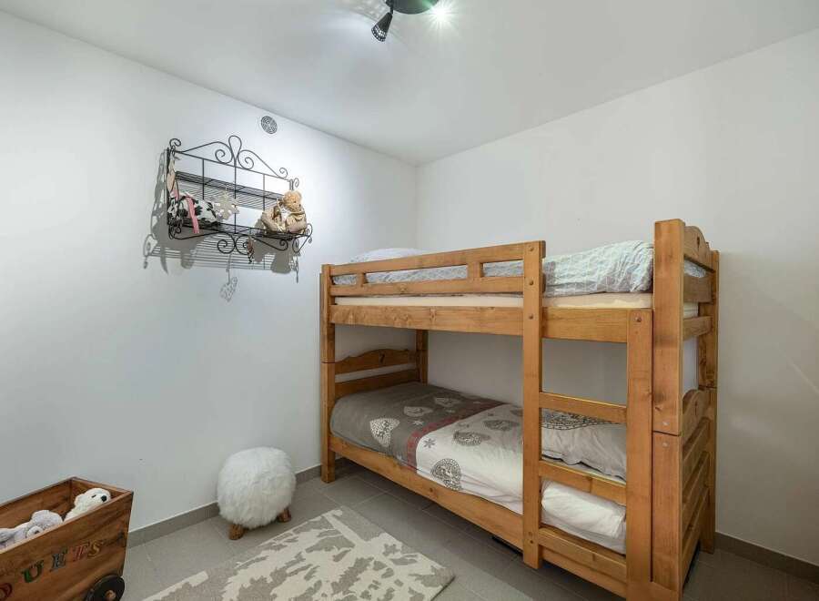 This charming children's bedroom features a sturdy wooden bunk bed, perfect for siblings or sleepovers.