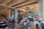 Experience rustic luxury in this stunning log cabin living space, featuring exposed wooden beams and a grand stone fireplace.