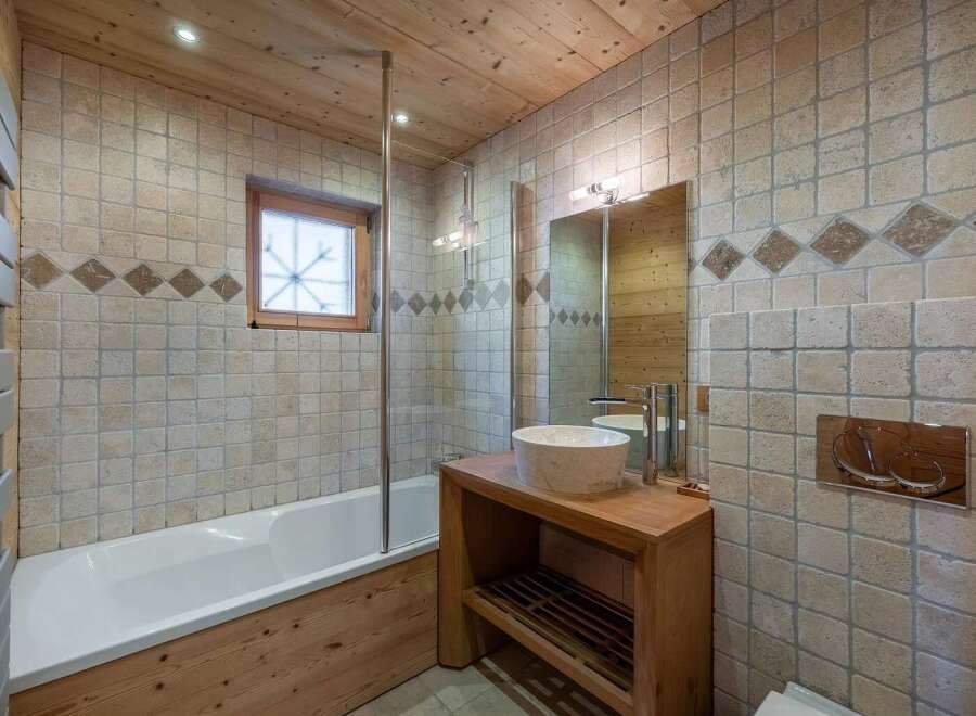 Experience rustic charm in this bathroom, featuring a deep soaking tub and a wooden vanity with a vessel sink.