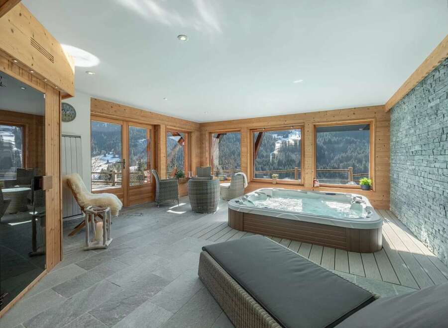 Indulge in ultimate relaxation in this luxurious indoor hot tub area, boasting panoramic mountain views through large windows.
