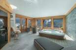 Indulge in ultimate relaxation in this luxurious indoor hot tub area, boasting panoramic mountain views through large windows.