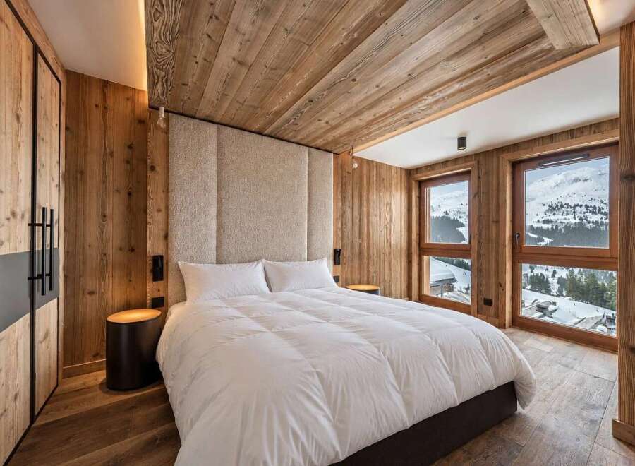 Experience luxury mountain living in this stunning bedroom featuring a plush king-sized bed and a dramatic upholstered headboard.